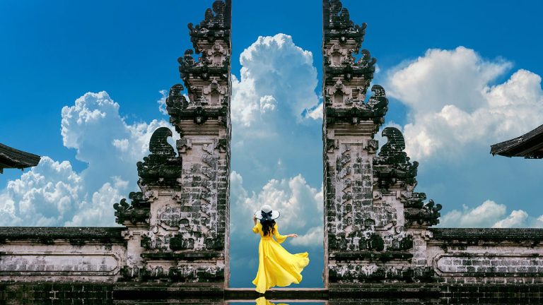 Young woman standing in temple gates at Lempuyang Luhur temple in Bali, Indonesia. Vintage tone.